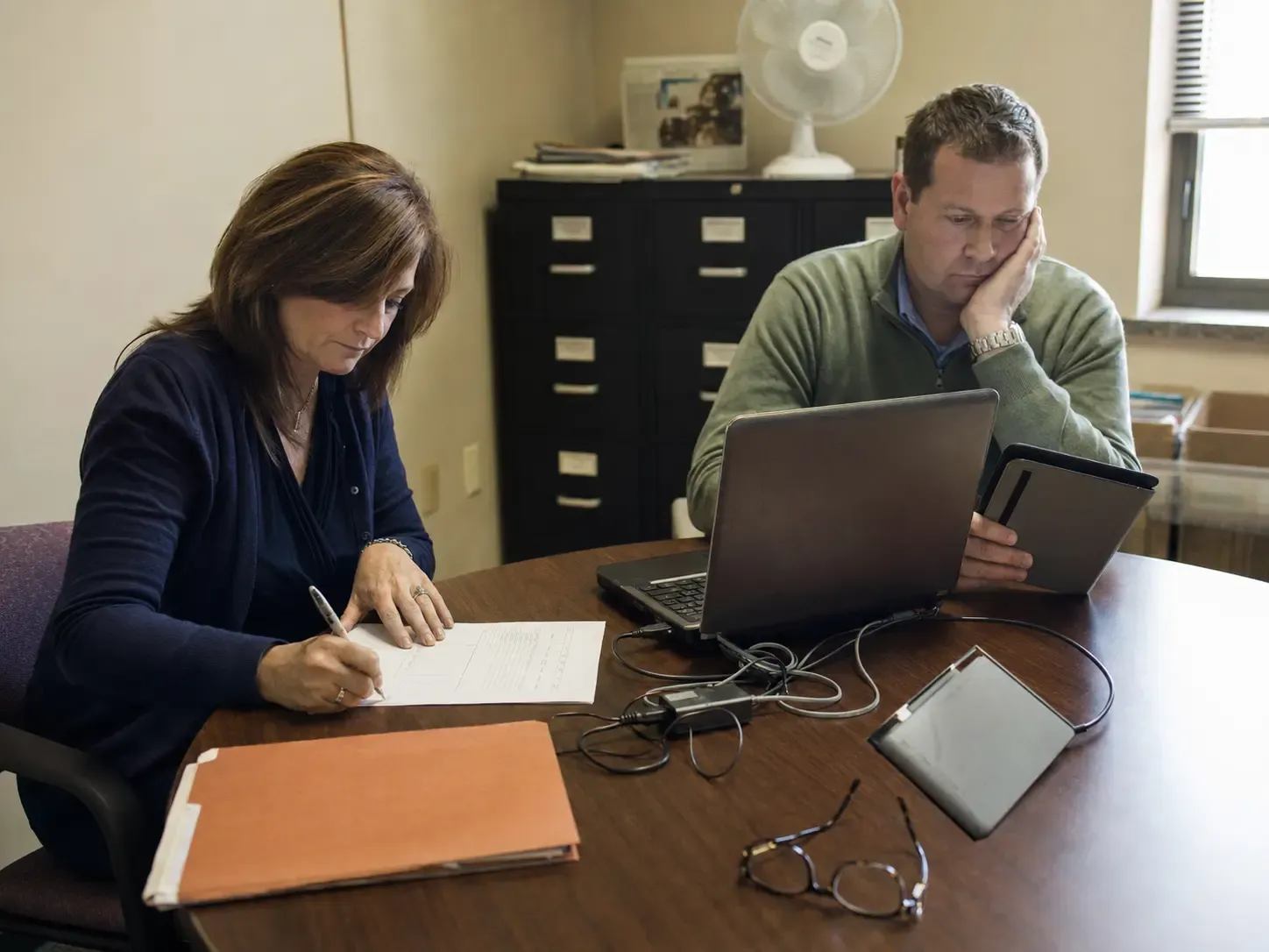 Two community leaders testing senior living admissions software on an older laptop and tablet